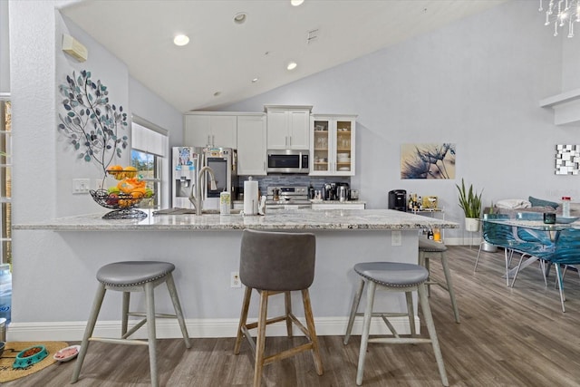 kitchen featuring white cabinetry, stainless steel appliances, kitchen peninsula, and a breakfast bar area