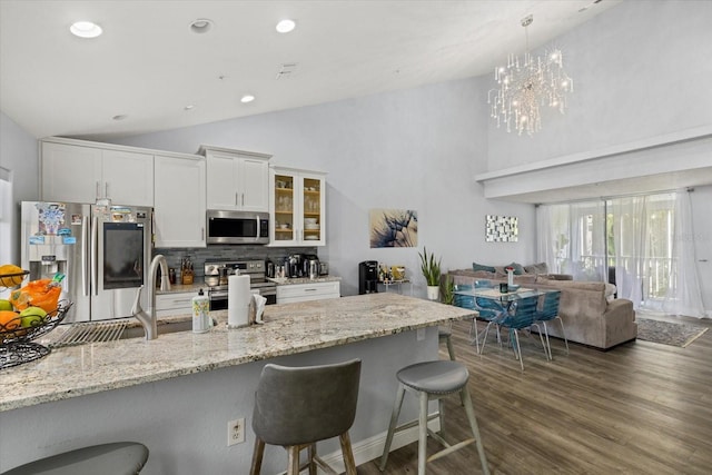 kitchen featuring appliances with stainless steel finishes, tasteful backsplash, white cabinetry, a breakfast bar area, and hanging light fixtures