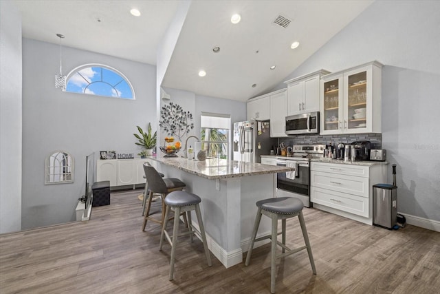 kitchen featuring white cabinetry, light stone counters, tasteful backsplash, and appliances with stainless steel finishes