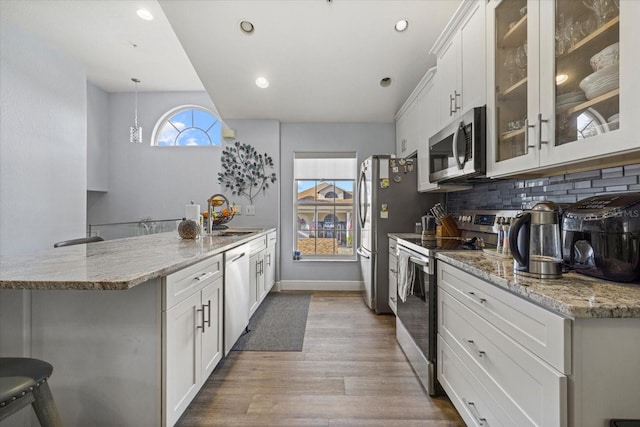 kitchen with white cabinetry, stainless steel appliances, sink, and hanging light fixtures