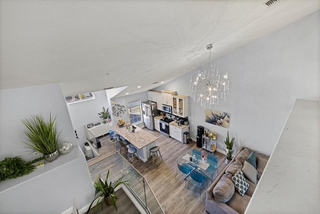 living room with hardwood / wood-style flooring, lofted ceiling, sink, and a notable chandelier