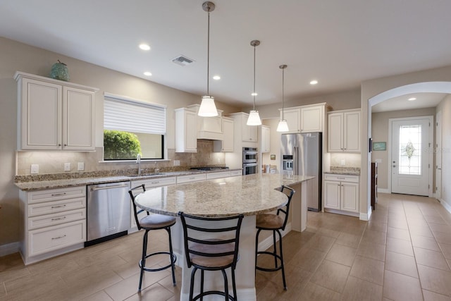 kitchen featuring appliances with stainless steel finishes, decorative light fixtures, a kitchen island, and white cabinets