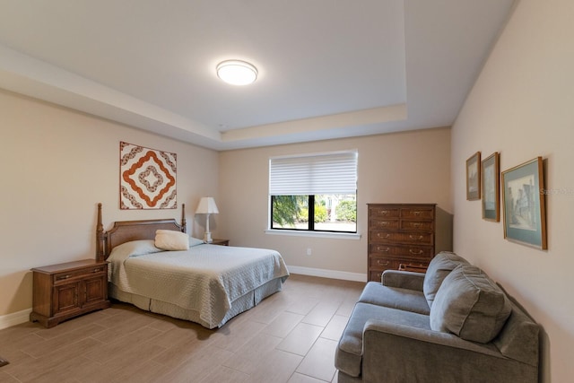 bedroom with a raised ceiling and light hardwood / wood-style floors