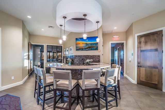 kitchen with pendant lighting, tasteful backsplash, a breakfast bar area, and light tile patterned floors