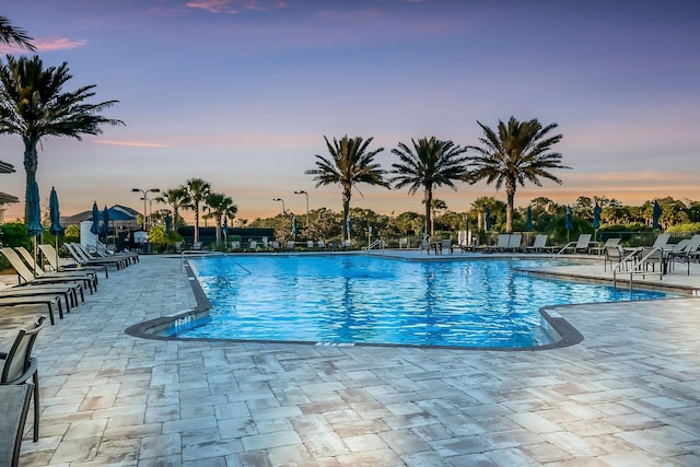 pool at dusk featuring a patio