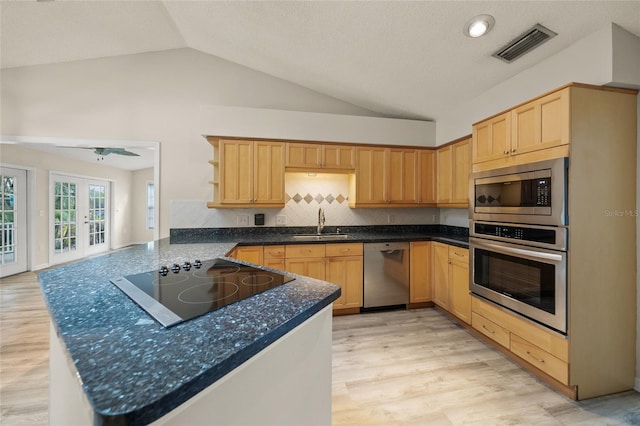 kitchen featuring vaulted ceiling, sink, kitchen peninsula, stainless steel appliances, and french doors