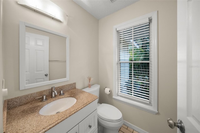 half bath with a textured ceiling, toilet, vanity, and baseboards