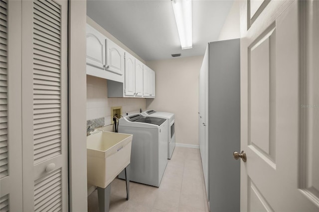 washroom with light tile patterned floors, sink, cabinets, and washing machine and clothes dryer