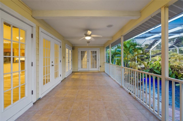 unfurnished sunroom with a ceiling fan, beam ceiling, and french doors