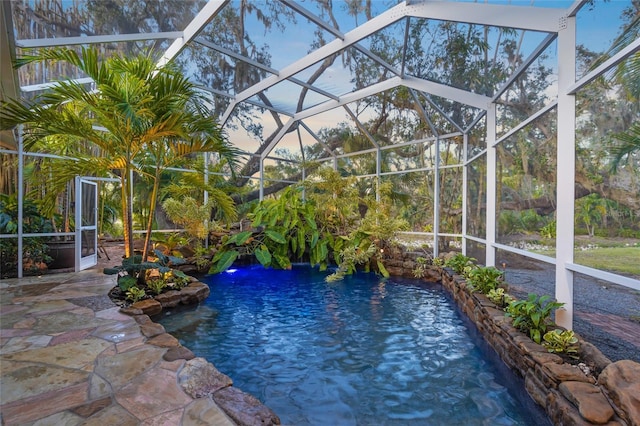 view of pool with pool water feature, glass enclosure, and a patio area