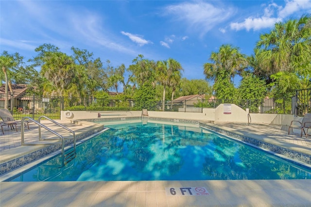 community pool with a patio and fence