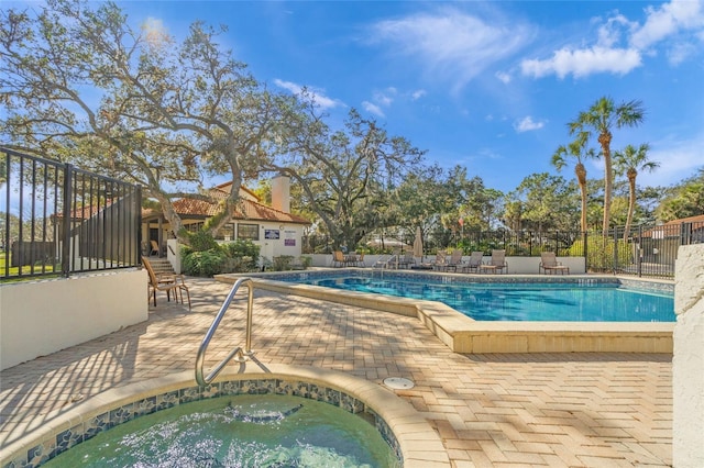 community pool featuring a community hot tub, a patio area, and fence