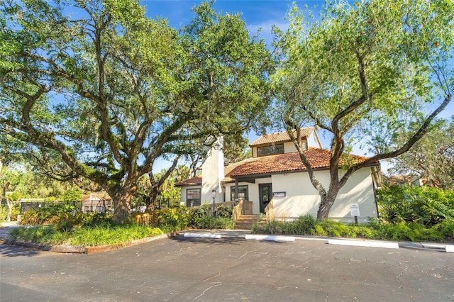 mediterranean / spanish-style house with uncovered parking, a tiled roof, and stucco siding