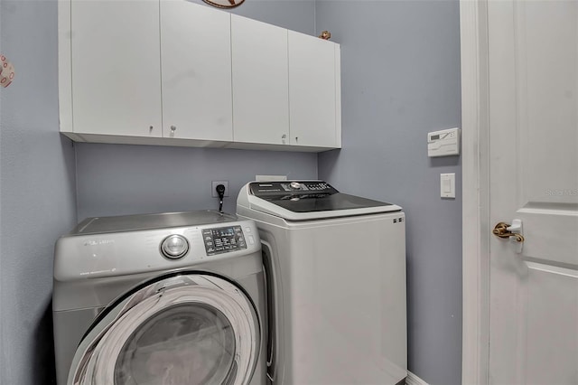 clothes washing area with cabinets and independent washer and dryer