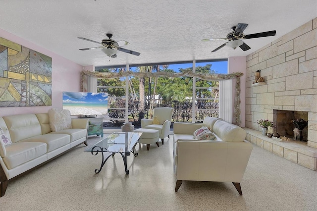 living room featuring ceiling fan, a fireplace, and a textured ceiling