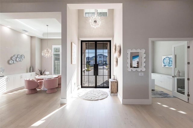 entrance foyer with light hardwood / wood-style flooring, french doors, and a chandelier