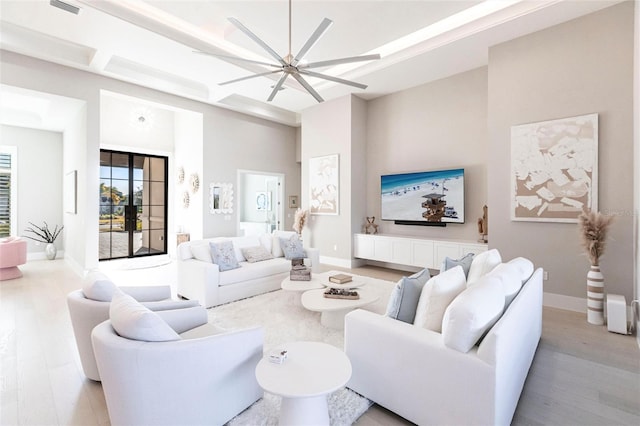 living room featuring coffered ceiling, beam ceiling, light hardwood / wood-style floors, and a high ceiling