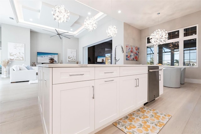 kitchen with white cabinetry, hanging light fixtures, light hardwood / wood-style floors, and an island with sink