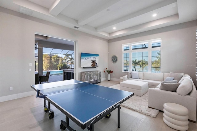 game room with plenty of natural light, beam ceiling, and light hardwood / wood-style flooring