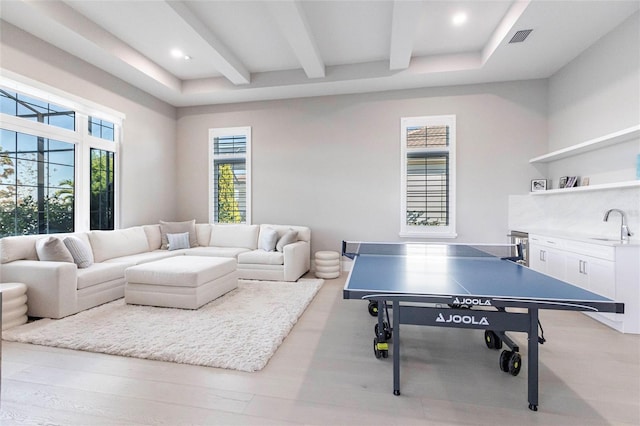 game room featuring sink, a wealth of natural light, light hardwood / wood-style floors, and beamed ceiling