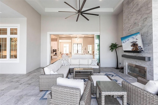 living room with ceiling fan, a fireplace, and a high ceiling