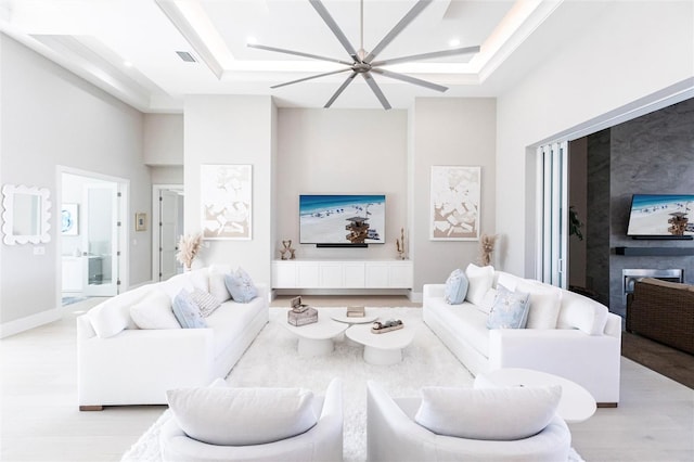 living room featuring a raised ceiling, a towering ceiling, and light hardwood / wood-style flooring