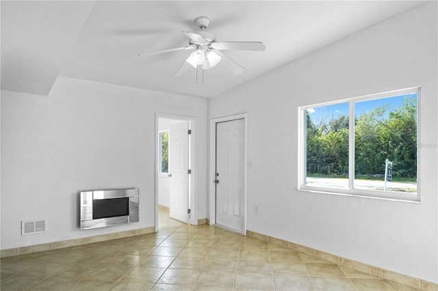 unfurnished living room with heating unit, light tile patterned floors, a fireplace, and ceiling fan