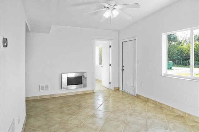 unfurnished living room with ceiling fan, plenty of natural light, a fireplace, and light tile patterned floors