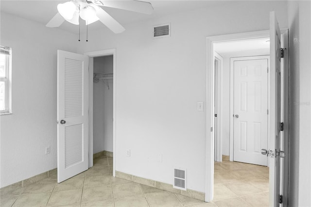 unfurnished bedroom featuring ceiling fan, a walk in closet, and light tile patterned floors