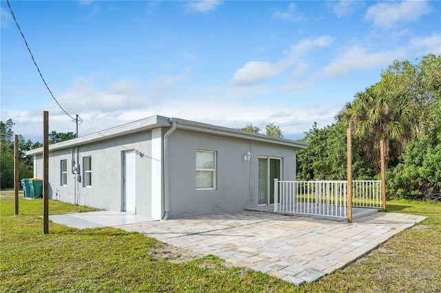 rear view of house with a patio and a lawn