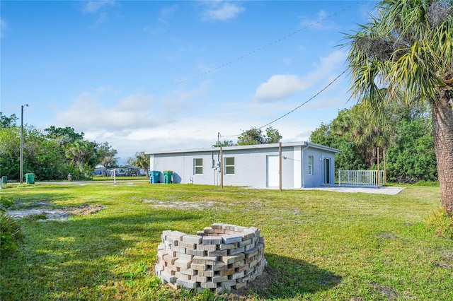 rear view of property featuring a patio area, a lawn, and an outdoor fire pit