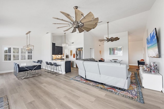 living room featuring sink, vaulted ceiling, ceiling fan, and light wood-type flooring