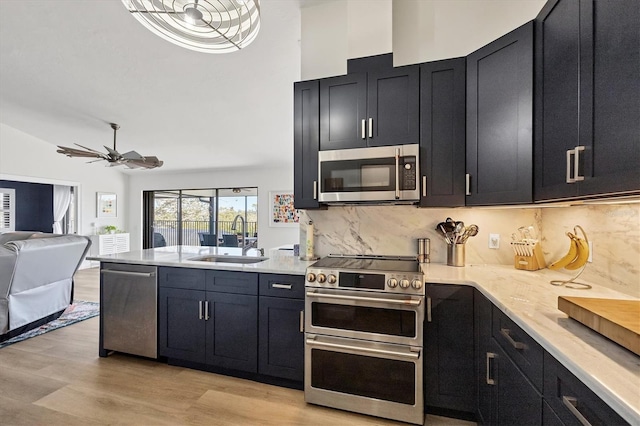 kitchen featuring sink, light wood-type flooring, appliances with stainless steel finishes, ceiling fan, and decorative backsplash