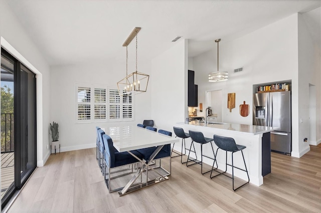 dining room featuring sink, a notable chandelier, and light hardwood / wood-style flooring