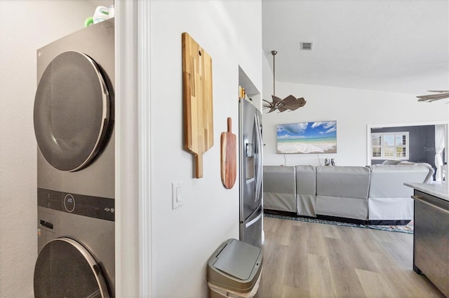 laundry area with light hardwood / wood-style floors and stacked washing maching and dryer