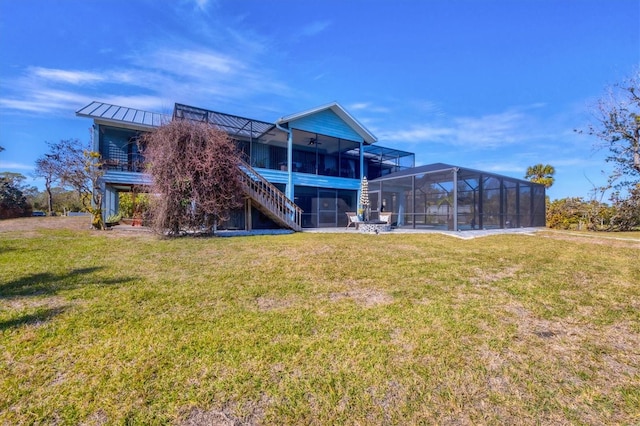 back of property with ceiling fan, a sunroom, and a lawn