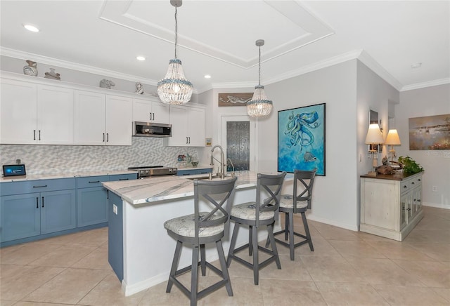 kitchen featuring stainless steel appliances, a breakfast bar, white cabinets, and a center island with sink