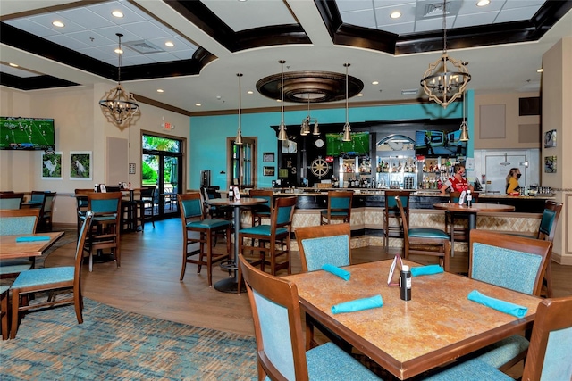 dining space with ornamental molding, wood-type flooring, and a notable chandelier