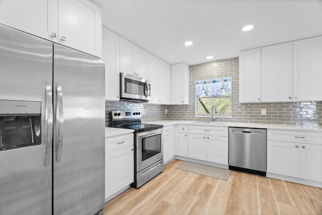 kitchen with white cabinetry, sink, stainless steel appliances, and light hardwood / wood-style floors