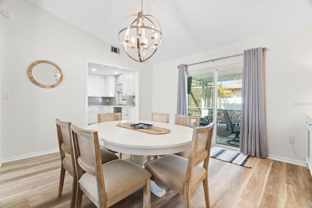 dining area featuring lofted ceiling, light wood-type flooring, and an inviting chandelier