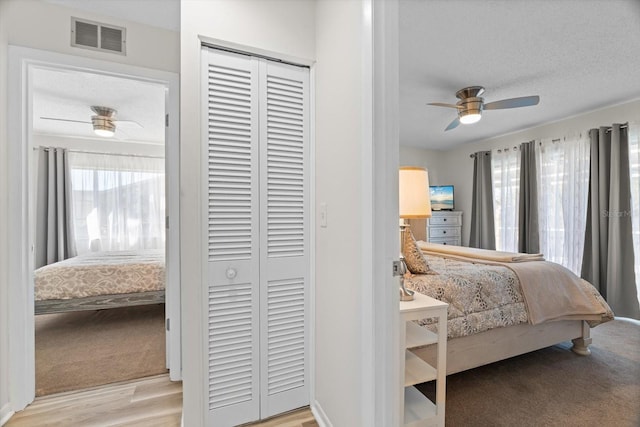 bedroom with ceiling fan, light colored carpet, a closet, and a textured ceiling