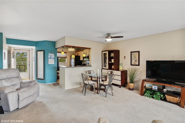 living room featuring light carpet, a textured ceiling, and ceiling fan