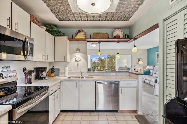 kitchen featuring light tile patterned flooring, sink, white cabinetry, decorative light fixtures, and appliances with stainless steel finishes