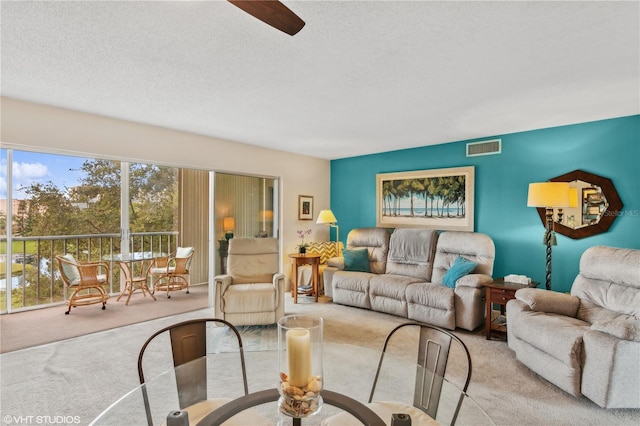 carpeted living room with ceiling fan and a textured ceiling