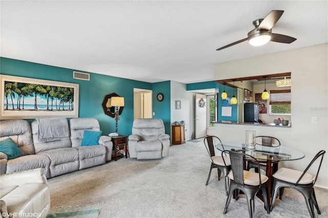 living room with ceiling fan, light carpet, and a textured ceiling