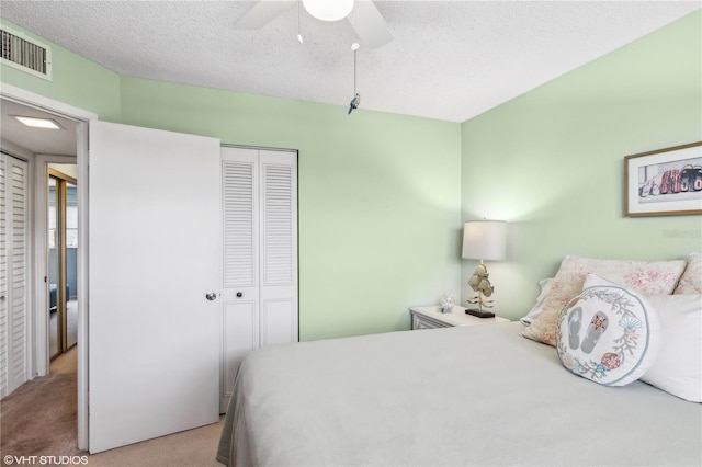 carpeted bedroom featuring ceiling fan, a closet, and a textured ceiling