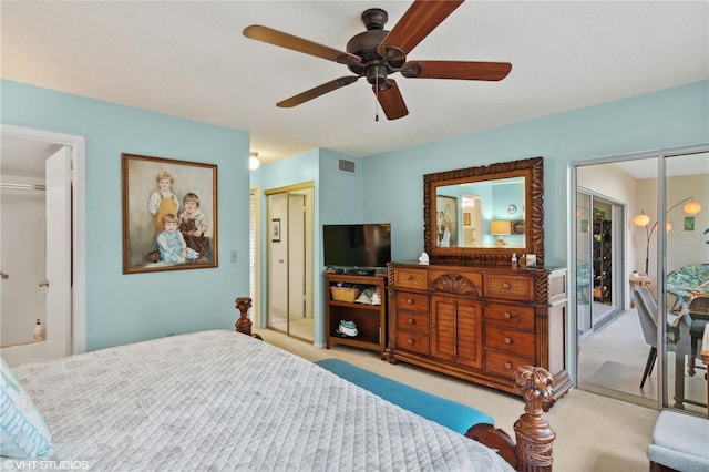 bedroom featuring light carpet, ceiling fan, and ensuite bath