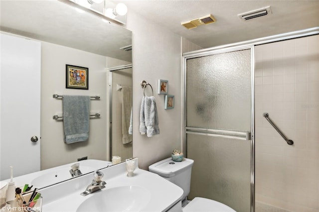 bathroom featuring vanity, a shower with door, and toilet