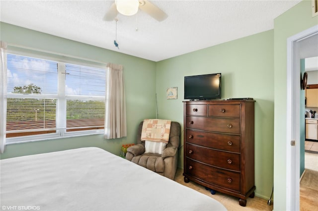 carpeted bedroom featuring ceiling fan and a textured ceiling