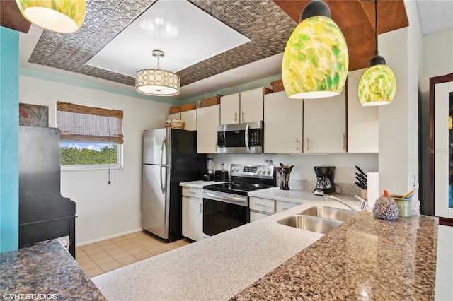 kitchen with sink, appliances with stainless steel finishes, a tray ceiling, pendant lighting, and white cabinets